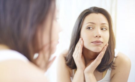 Woman checking her skin in a mirror