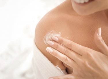 Mujer aplicándose crema en la piel