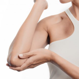 Mujer hidratandose los codos con producto bioderma Mujer hidratandose los codos con producto bioderma