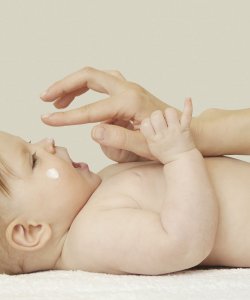 Madre aplicando crema a bebé
